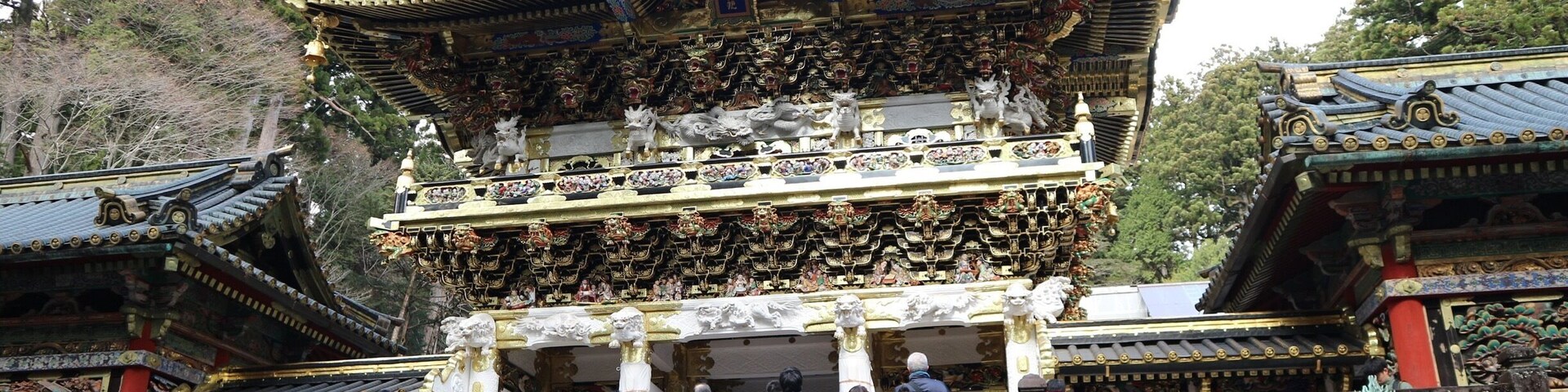 Un templo japonés tradicional con arquitectura ornamentada, una escalera que conduce a la entrada y un farol de piedra.