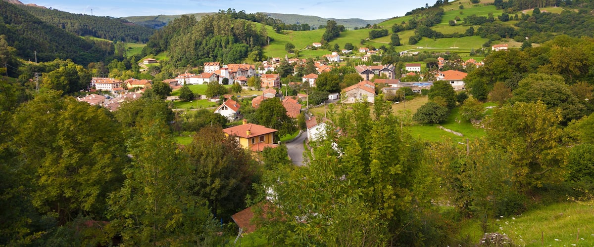 A village nestled in a valley surrounded by lush green hills.
