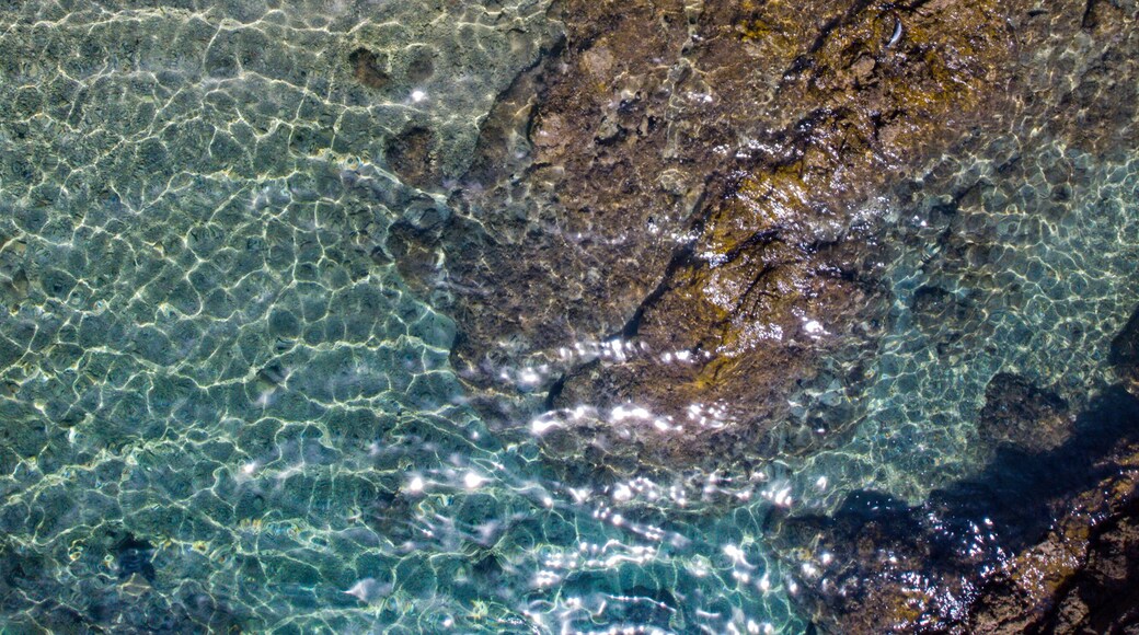 top down view of a girl in a bikini lying on the sand on the seashore; relaxing on a paradise beach as seen from a drone; a beautiful model lying on the sand
