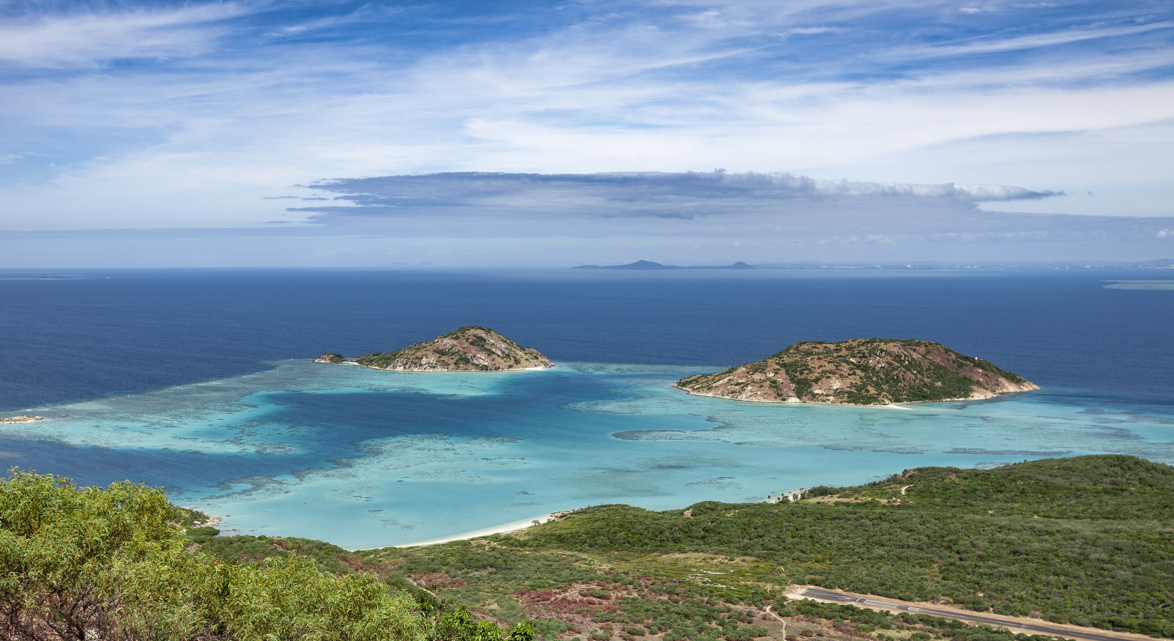 A coastal landscape with two prominent hills and a clear blue sea.