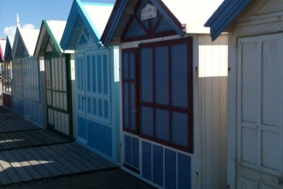 A row of colorful wooden buildings with blue and white facades and red doors.
