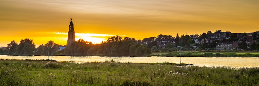 Ein Fluss mit einem Turm im Hintergrund bei Sonnenuntergang.