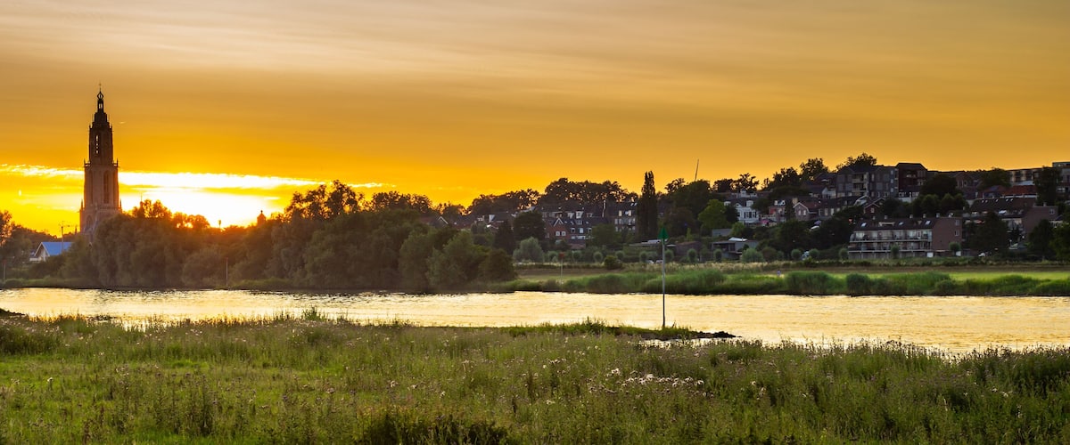 A river with a tower in the background during sunset.