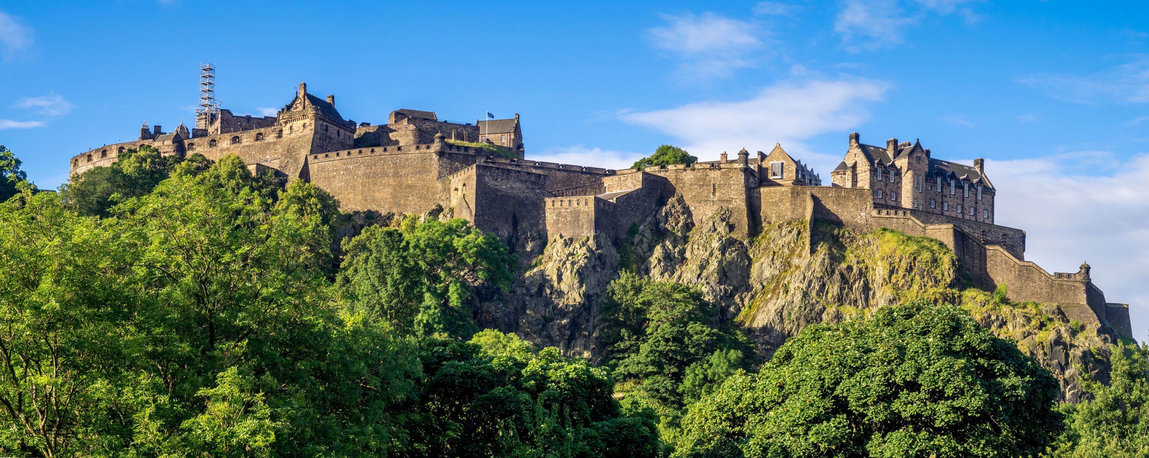 A historic castle on a hill with dense green foliage.