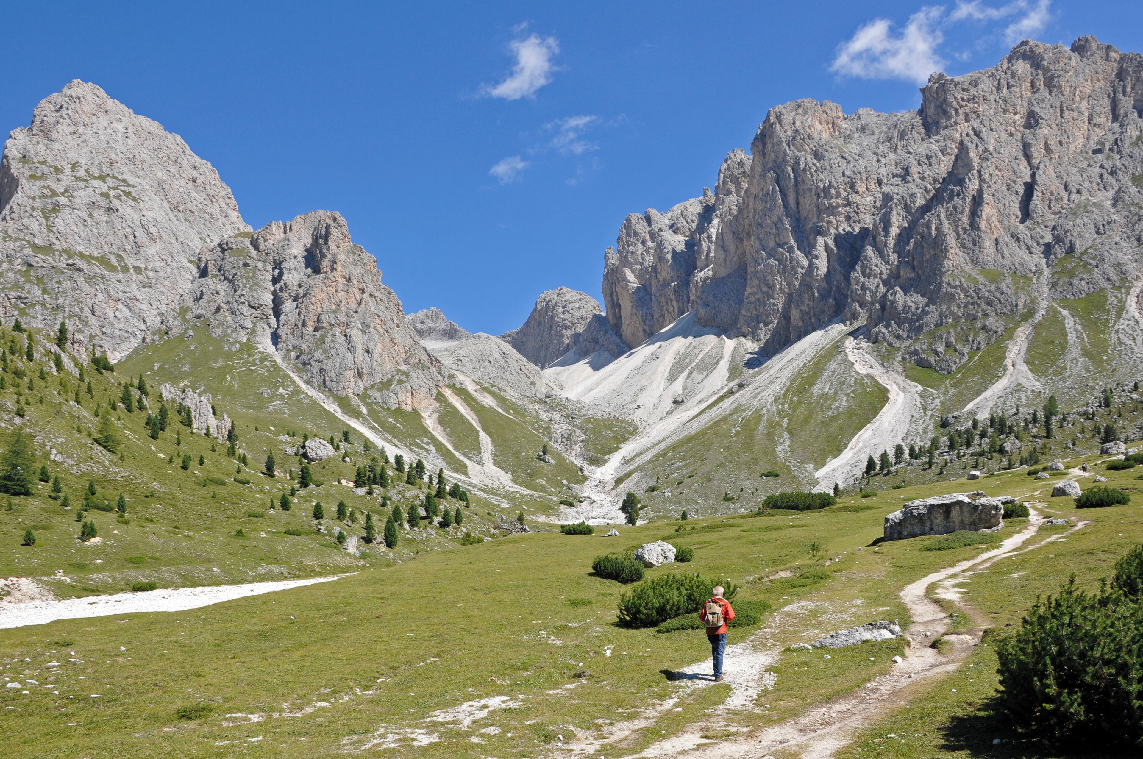 A hiker on a trail with mountains in the background.