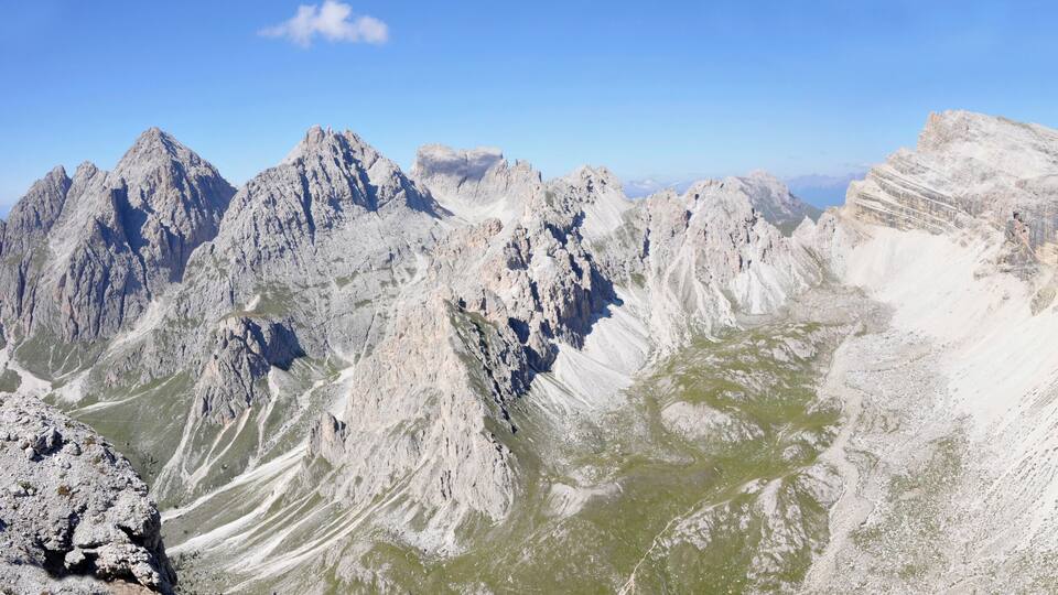 Rugged mountain peaks with sparse vegetation and a clear blue sky.