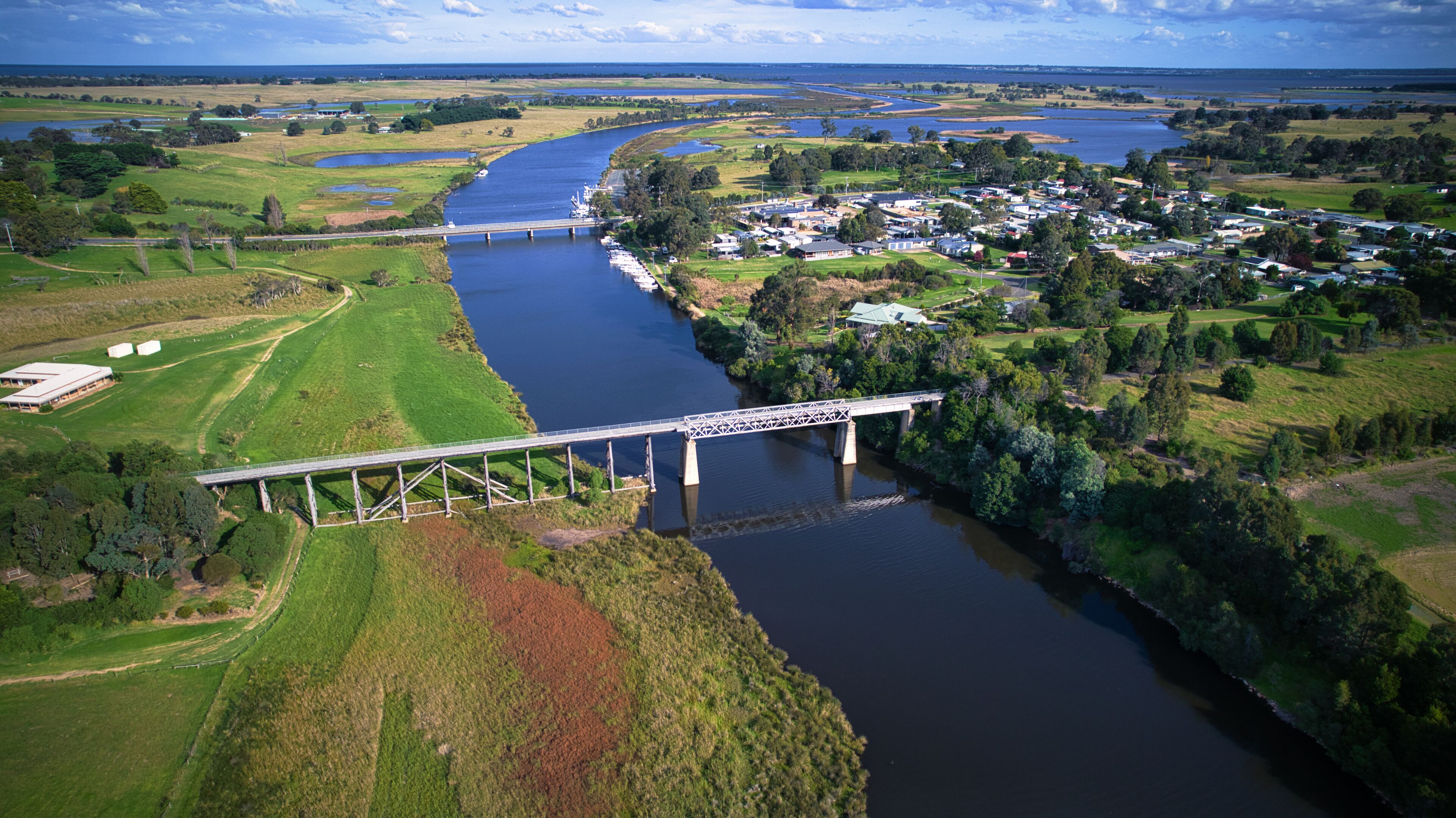 A river with a bridge, green fields, and a small town.