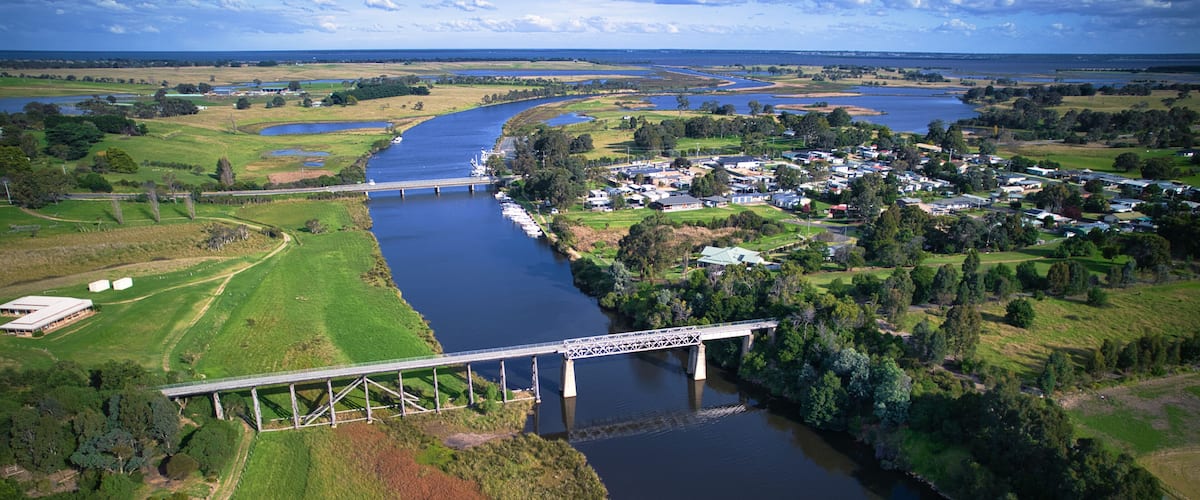 A river with a bridge, green fields, and a small town.