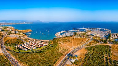 An aerial view of a coastal city with a marina, residential areas, and surrounding hills.