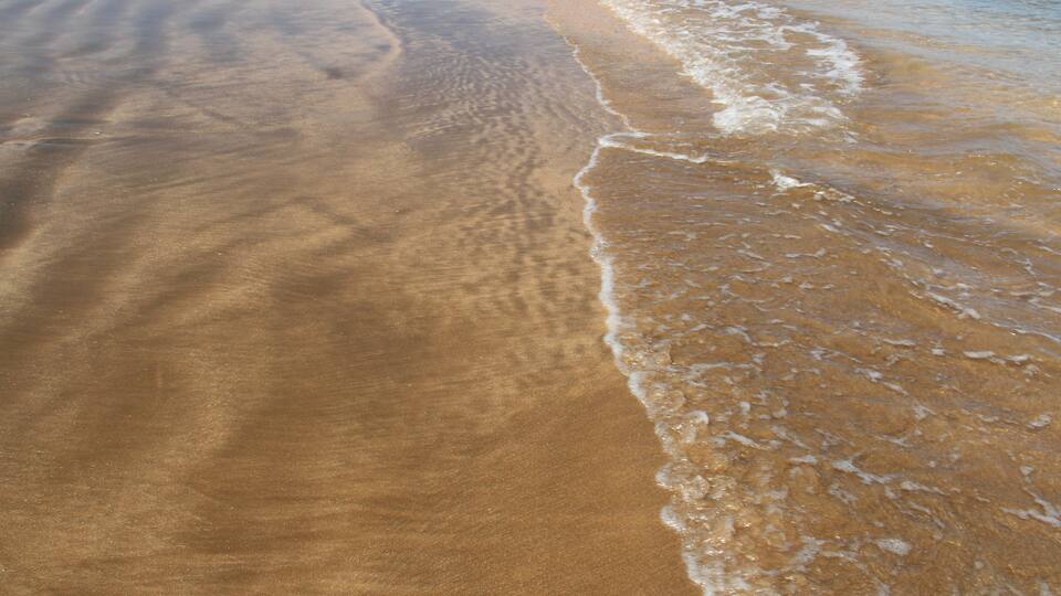 A sandy beach with gentle waves lapping at the shore.