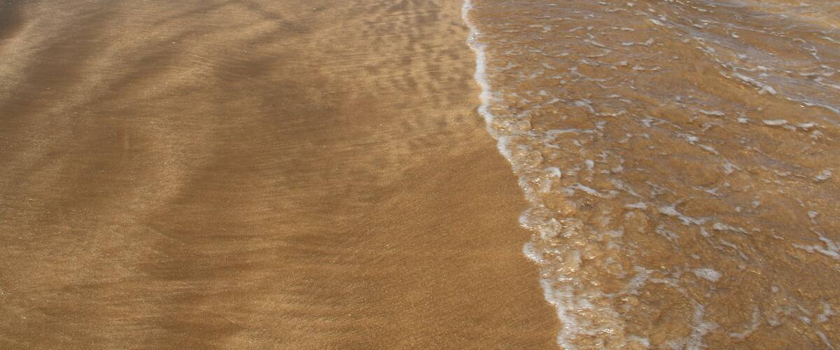 A sandy beach with gentle waves lapping at the shore.