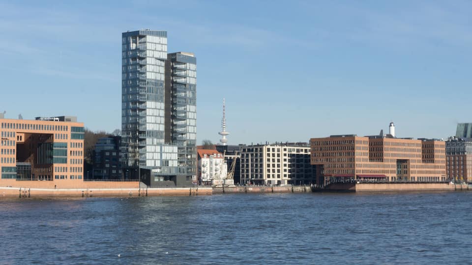 A city skyline with modern buildings, a river, and a tower in the background.
