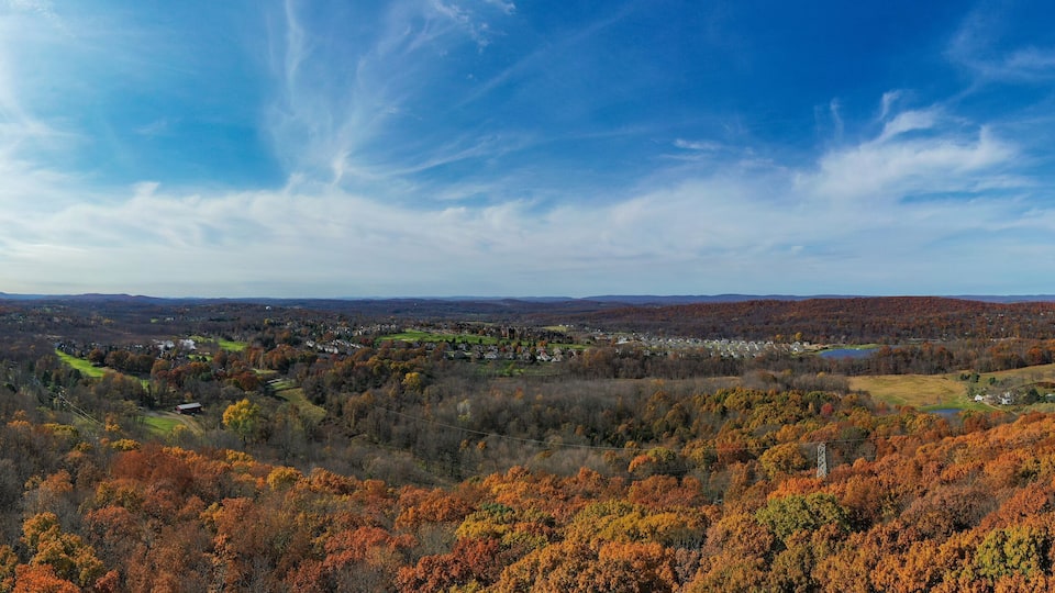 A valley with autumn foliage, a town in the distance, and rolling hills.
