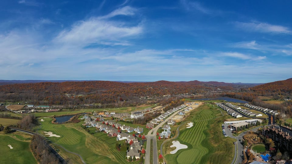 A golf course with a residential area and autumn-colored trees in the background.