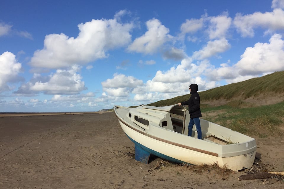 Een boot op een zanderig strand, met een persoon ernaast.