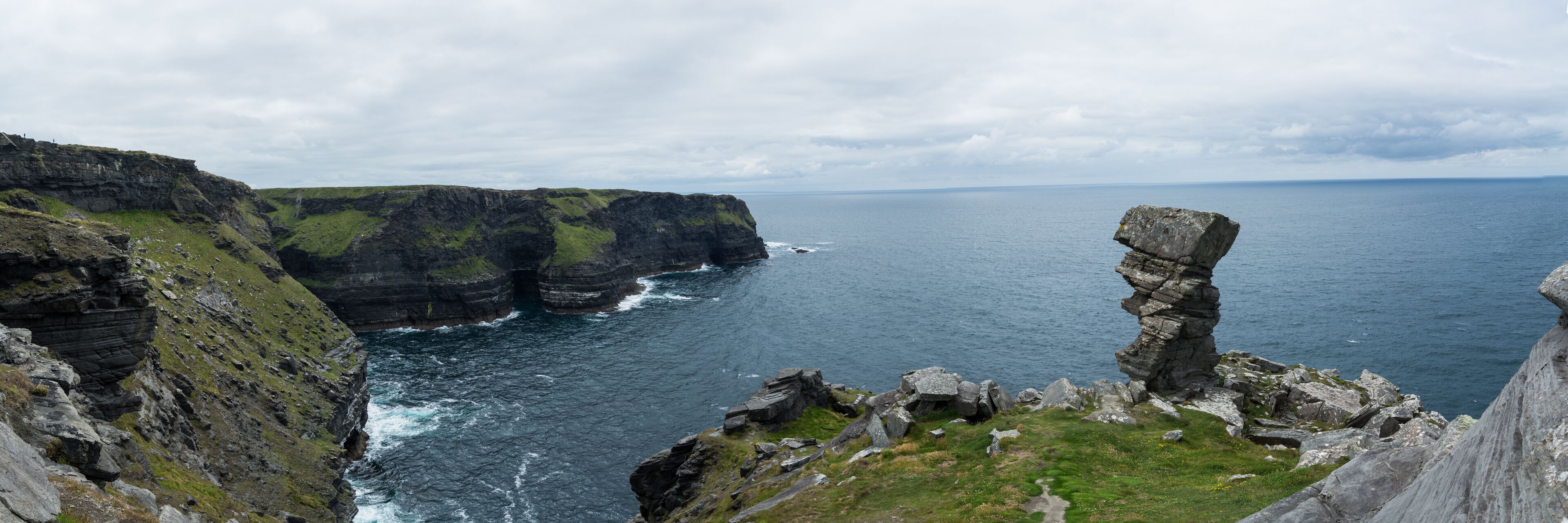 A coastal cliff with a prominent rock formation.