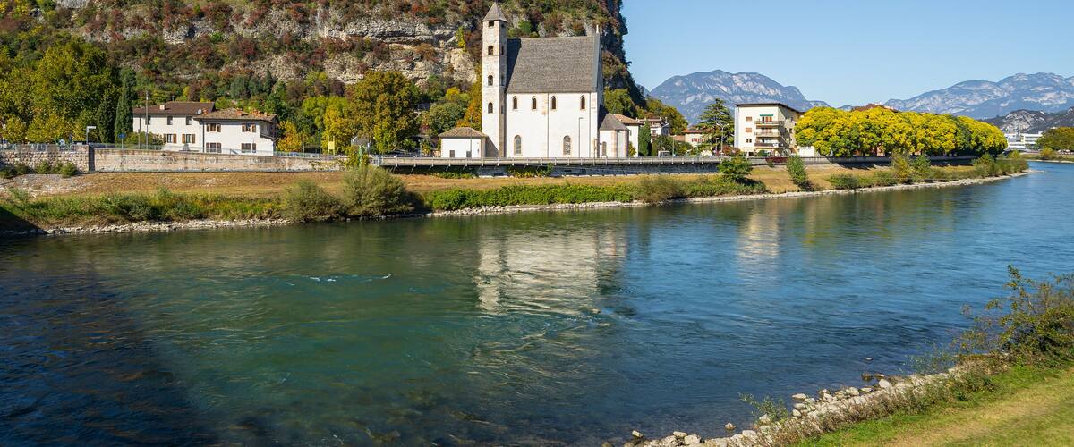 A river with a church and buildings on a hillside.