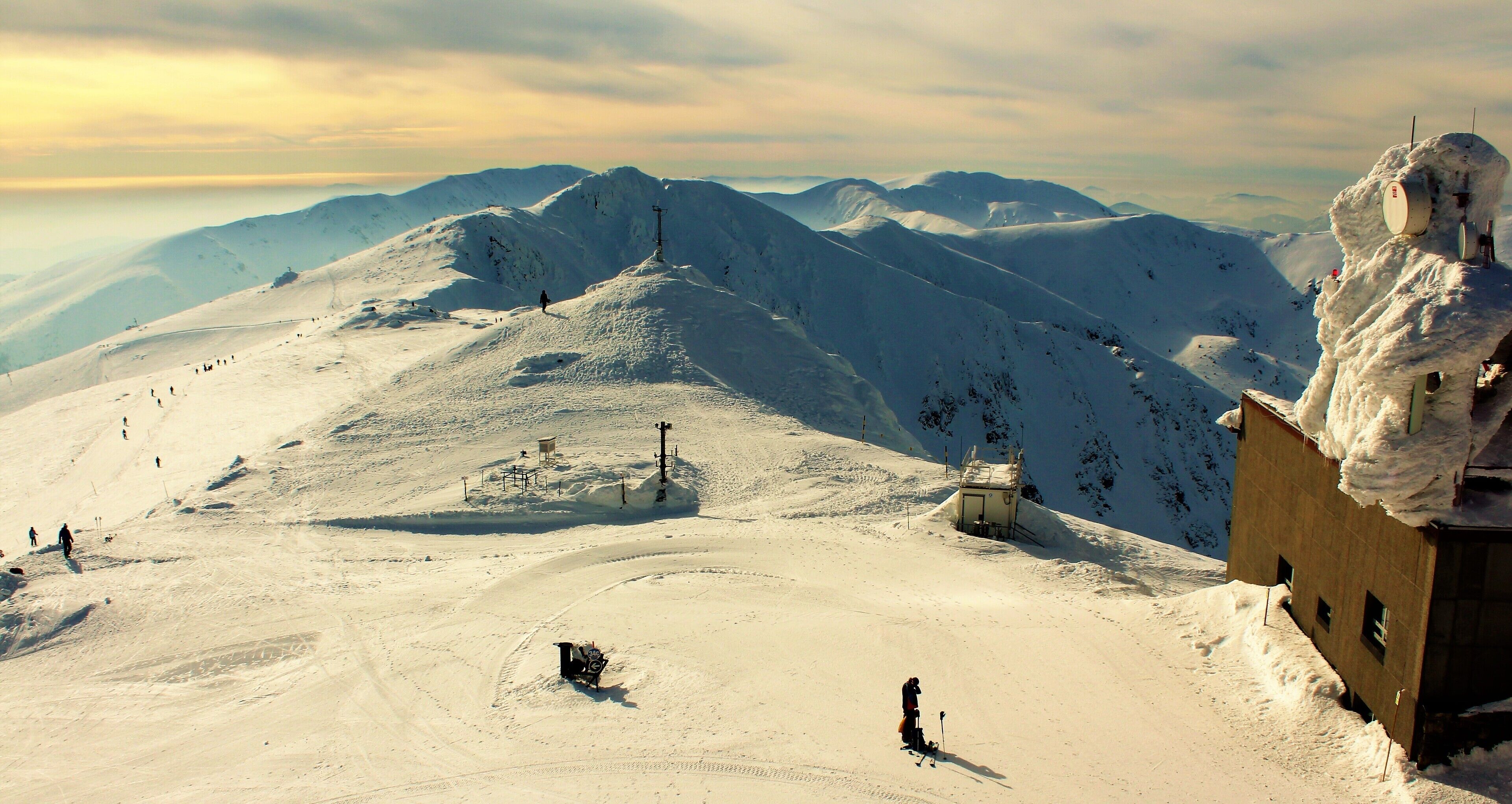 A snow-covered mountain landscape with ski trails, a ski lift, and a small cabin.