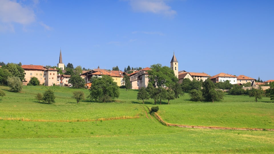 A town with a prominent church and a tall tower, surrounded by green fields and trees.