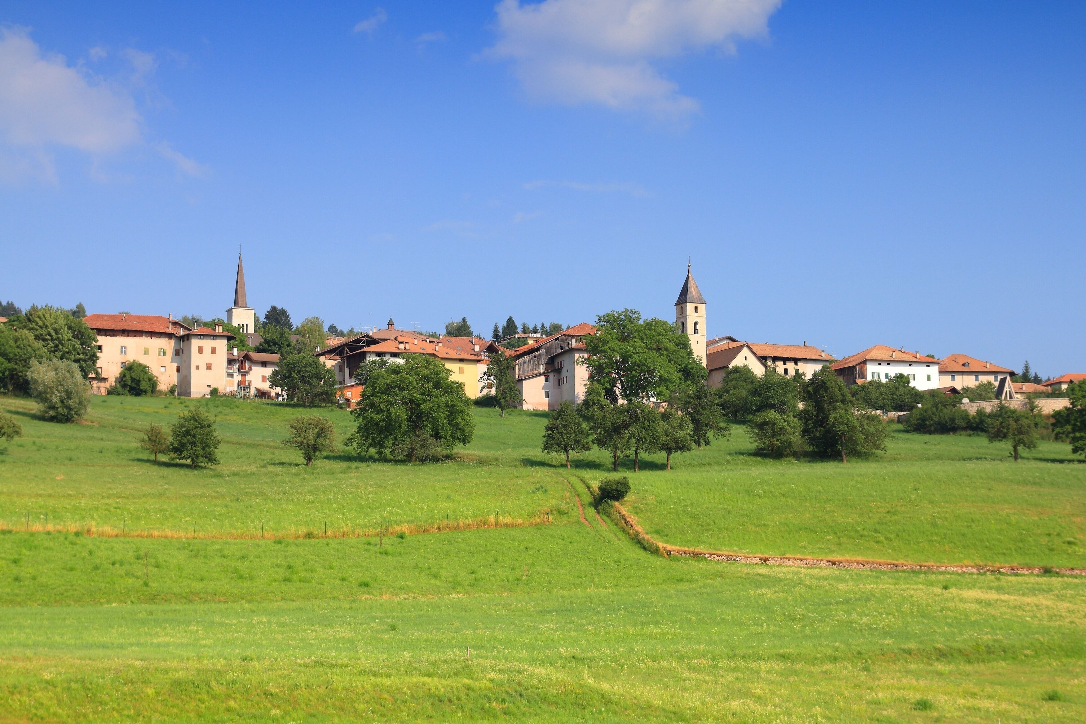 A town with a prominent church and a tall tower, surrounded by green fields and trees.