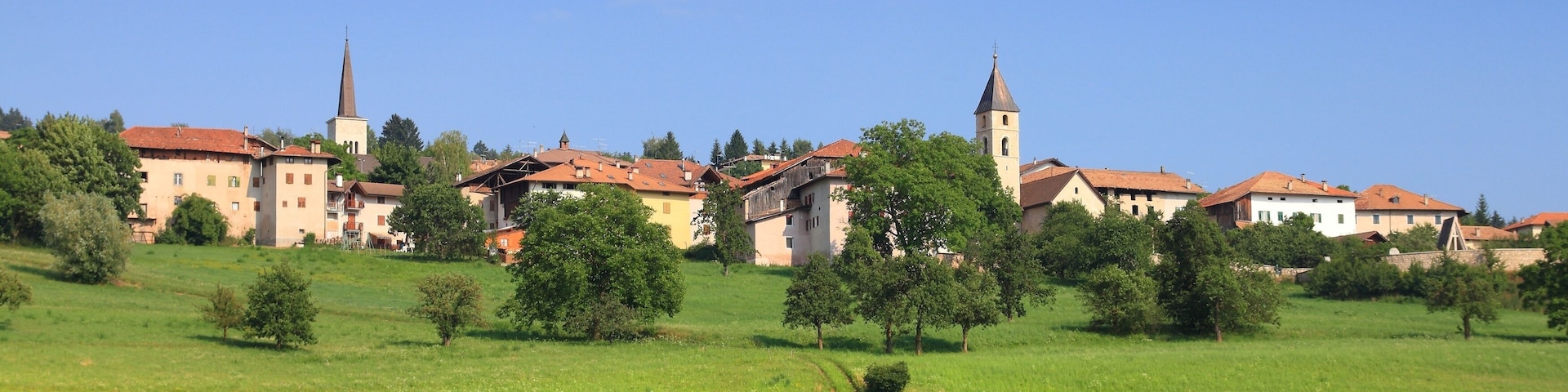 A town with a prominent church and a tall tower, surrounded by green fields and trees.