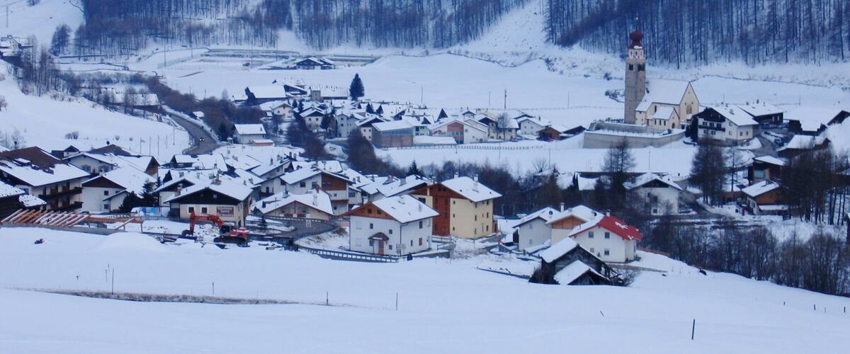 A snow-covered village with houses, a church, and a mountain backdrop.