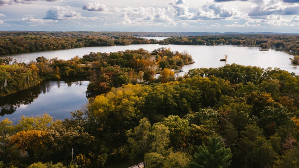 Drone photograph of gorgeous lake with forest of fall trees