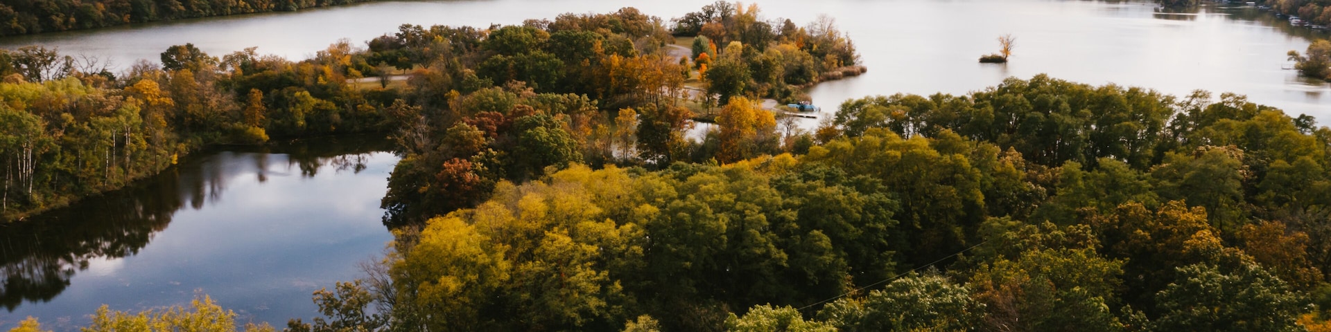 Un lago rodeado de bosque denso con una carretera que lo bordea.