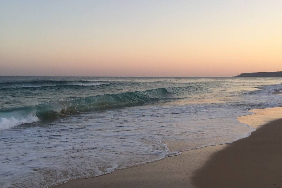 Een strand met golven bij zonsondergang.