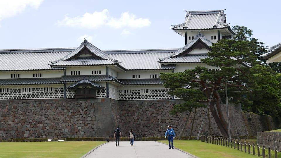 A traditional Japanese castle with stone walls and tiled roofs.