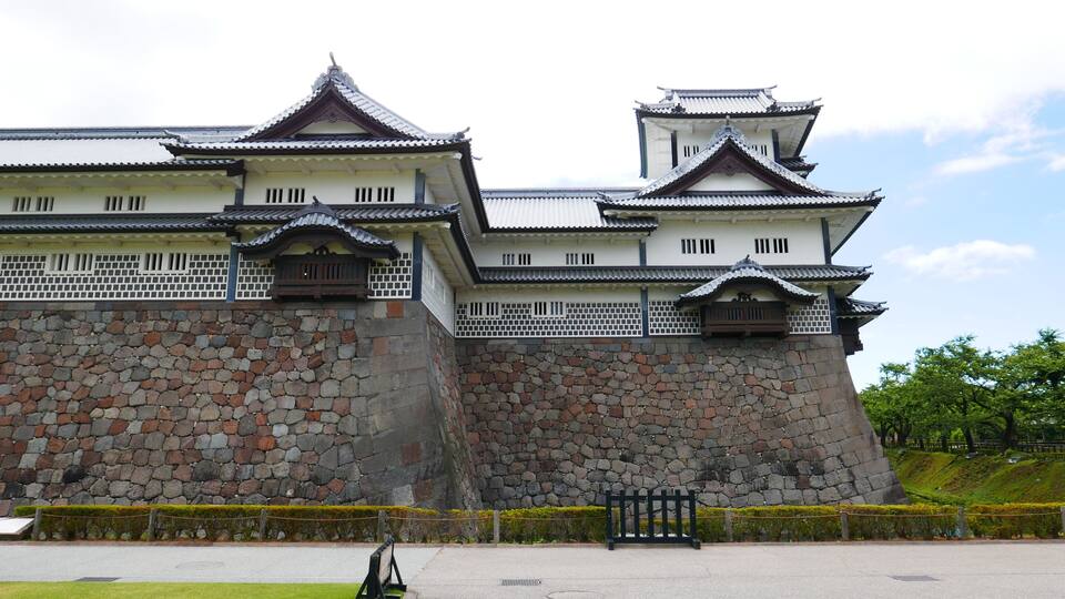 A traditional Japanese castle with multiple tiers, stone walls, and wooden gates.