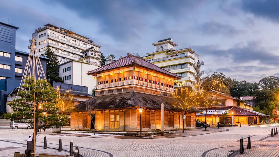 A traditional Japanese building with a wooden facade and tiled roof, surrounded by modern high-rise buildings.