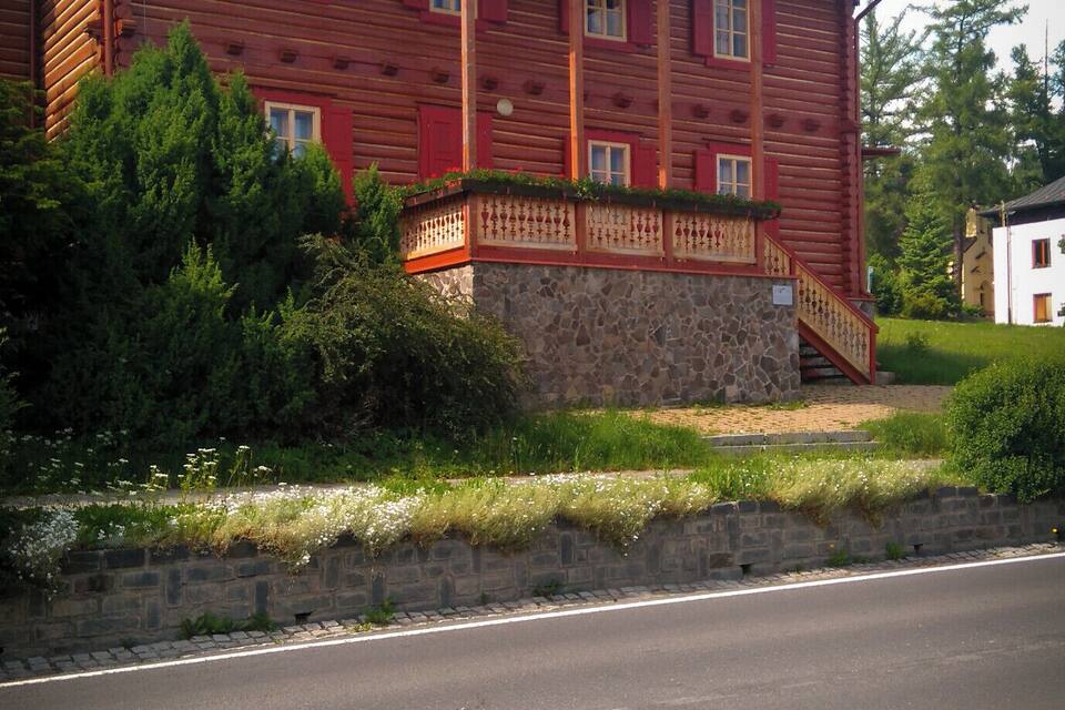 A red wooden building with a stone foundation and a porch.