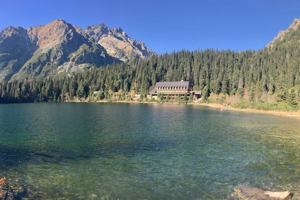 A mountain lake with a lodge surrounded by dense forest and rocky mountains.