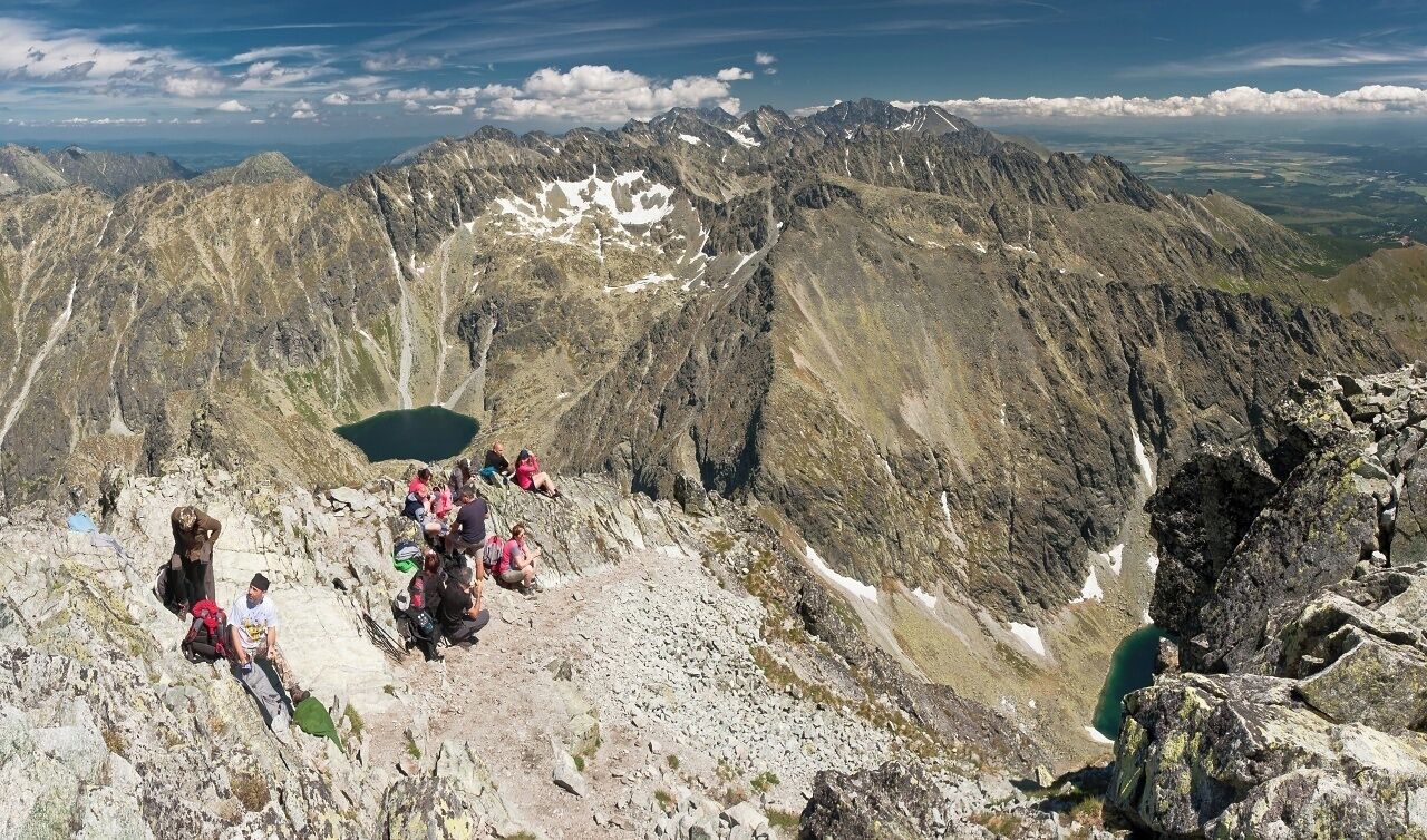 A mountainous landscape with hikers and a lake.