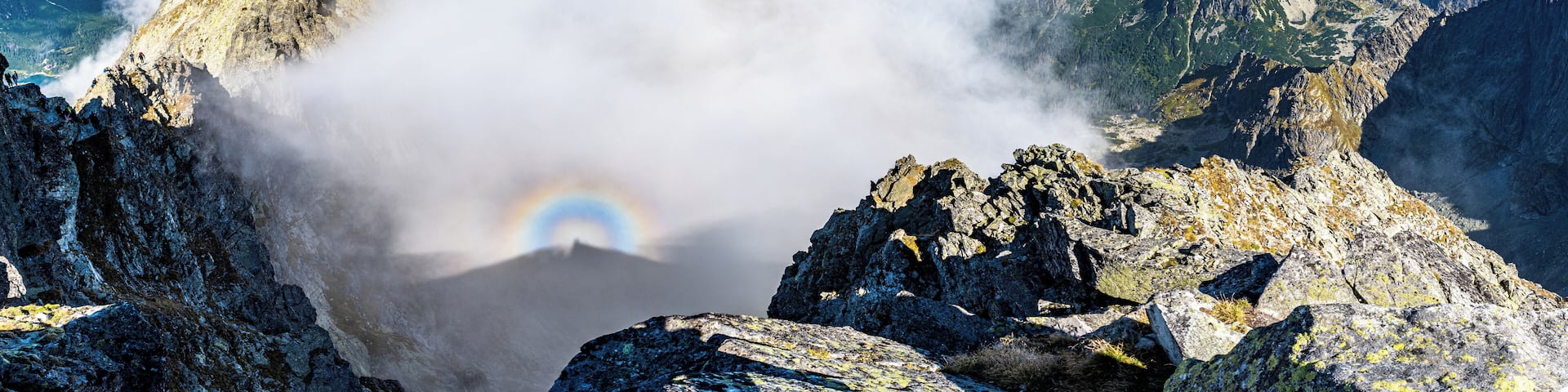 A mountain peak with a rainbow and clouds.