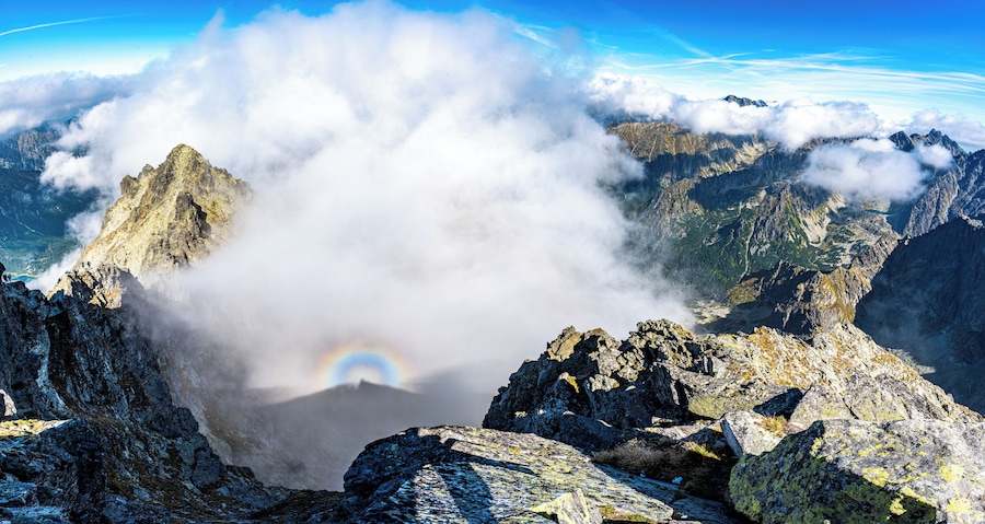 Un pico montañoso con un arcoíris y nubes.