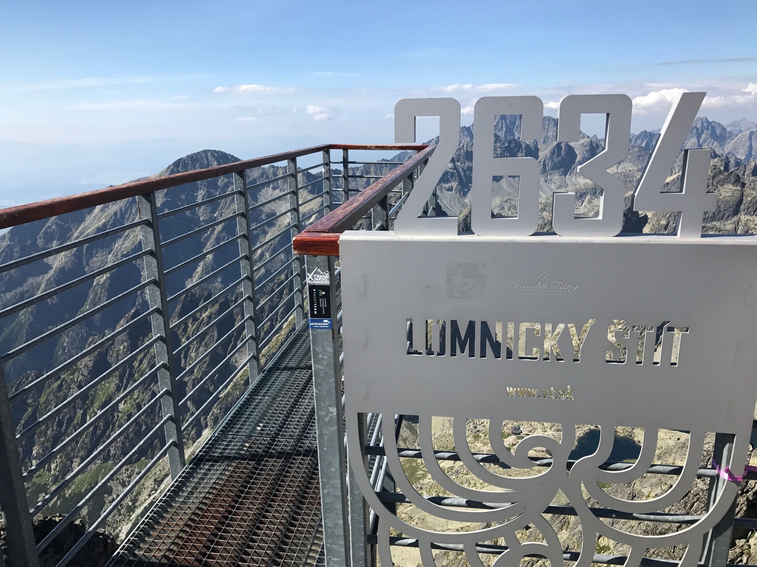 Una escalera metálica con un cartel que dice "2634 LUMNICKY ST" y vistas de montañas al fondo.