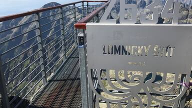 Una escalera metálica con un cartel que dice "2634 LUMNICKY ST" y vistas de montañas al fondo.