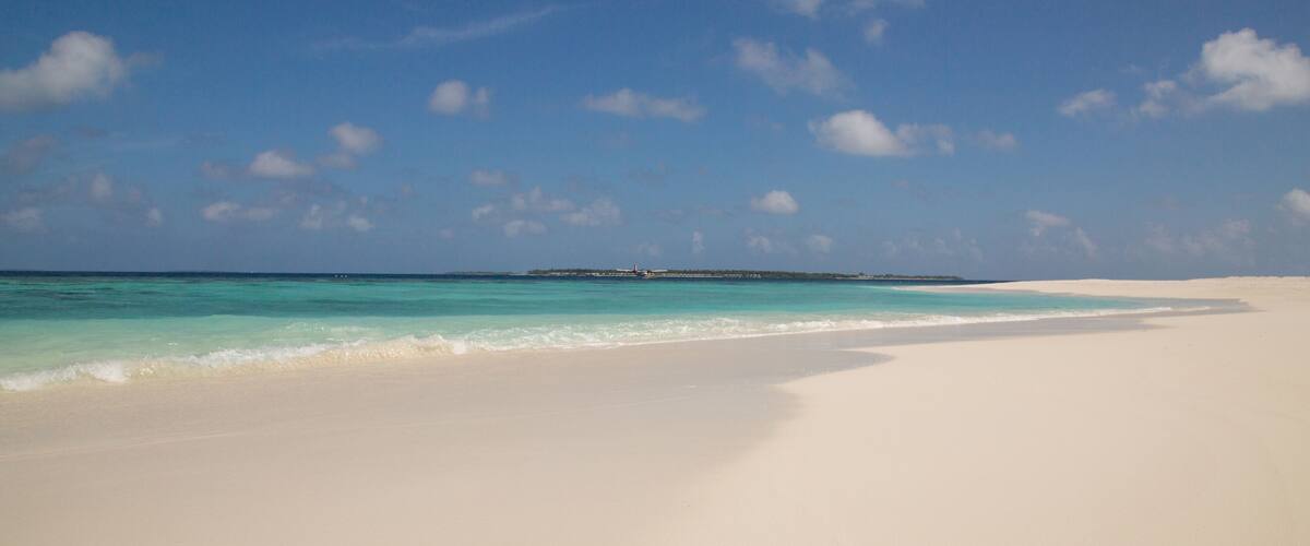 A beach with white sand and turquoise water.