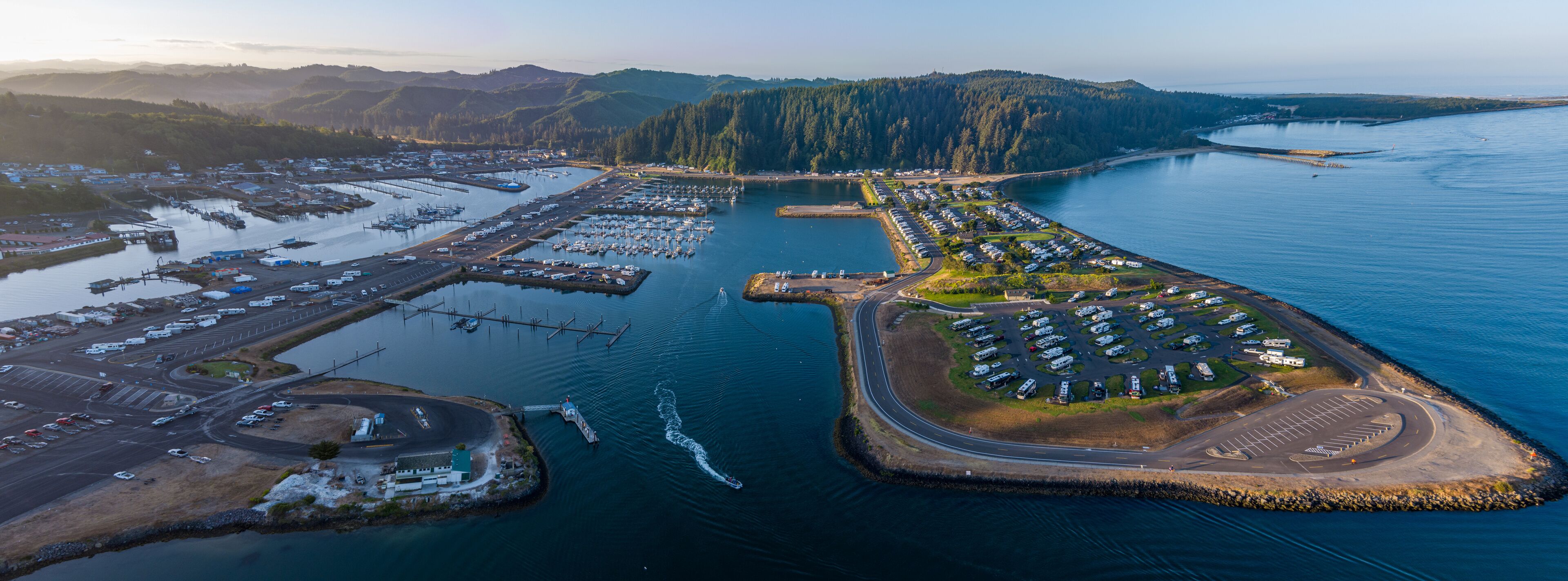 Aerial View of Winchester Bay, Oregon with the Harbor, Marina, a Rv Park and Fishing boats at sunrise.