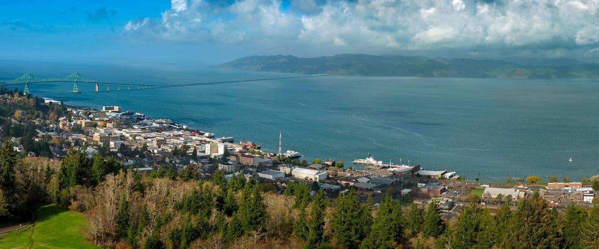 Historic Astoria, Oregon, USA. This view of the Astoria skyline is from the Astoria Column on a hill above the city featuring the beautiful Columbia River and the Astoria–Megler Bridge.