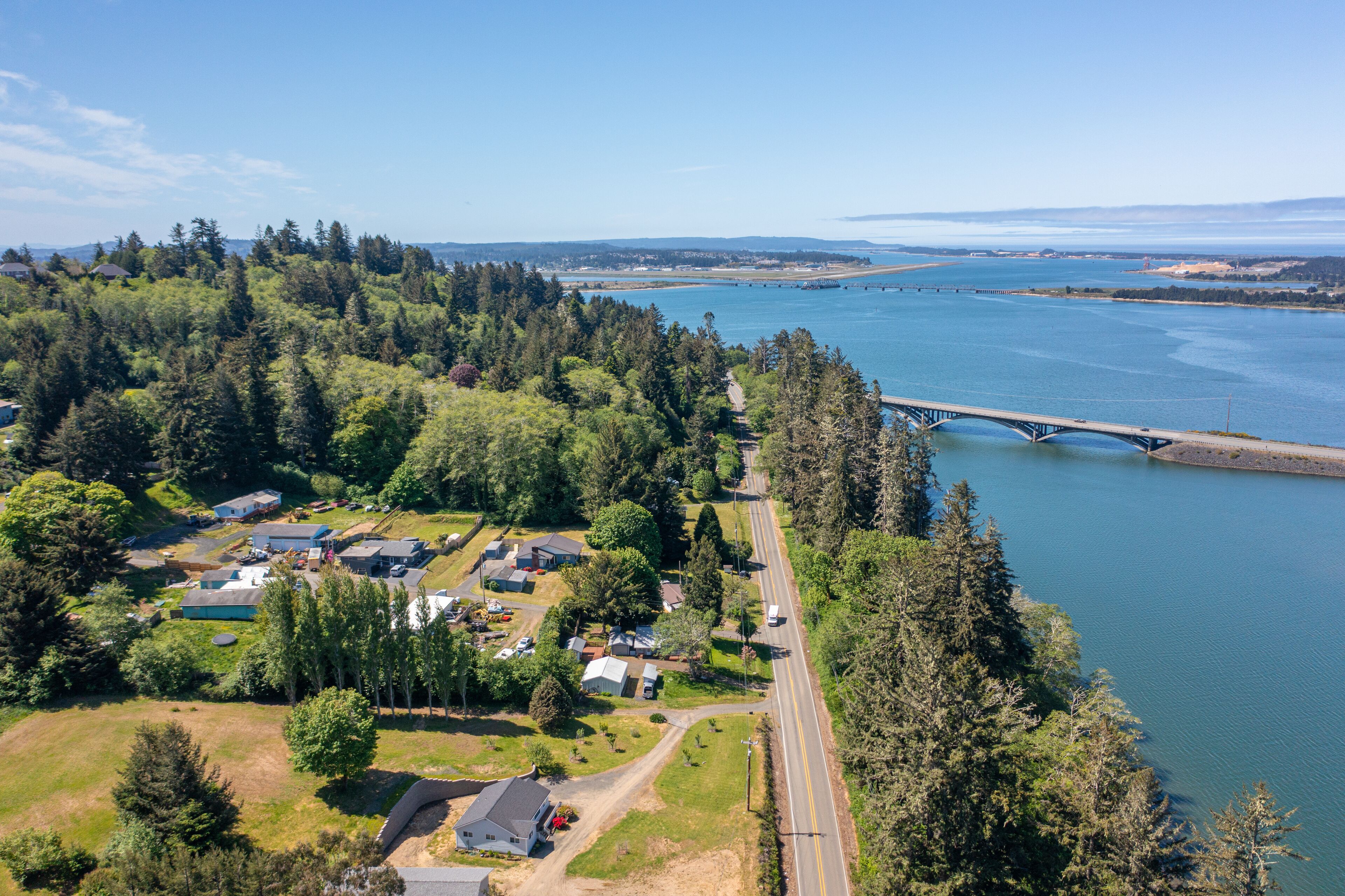 An aerial view of a residential area with houses, a road, and a bridge over a river.