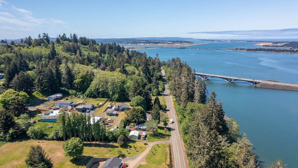 An aerial view of a residential area with houses, a road, and a bridge over a river.