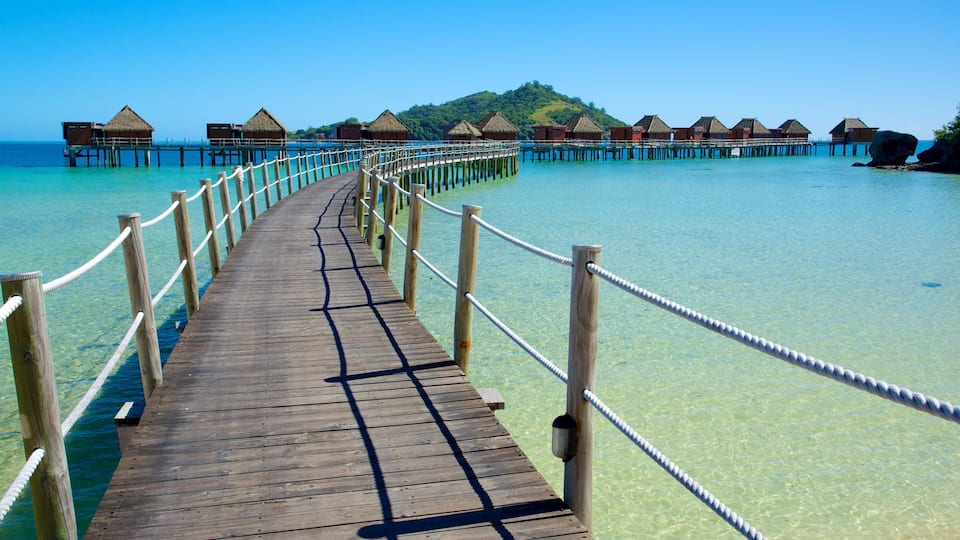 A wooden pier leading to overwater bungalows with clear turquoise water.