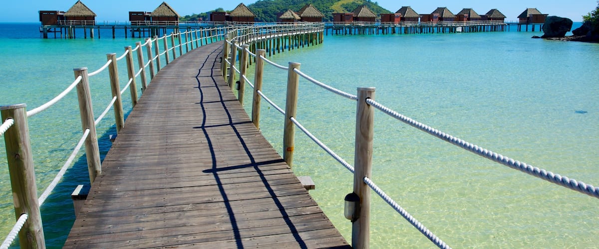 A wooden pier leading to overwater bungalows with clear turquoise water.