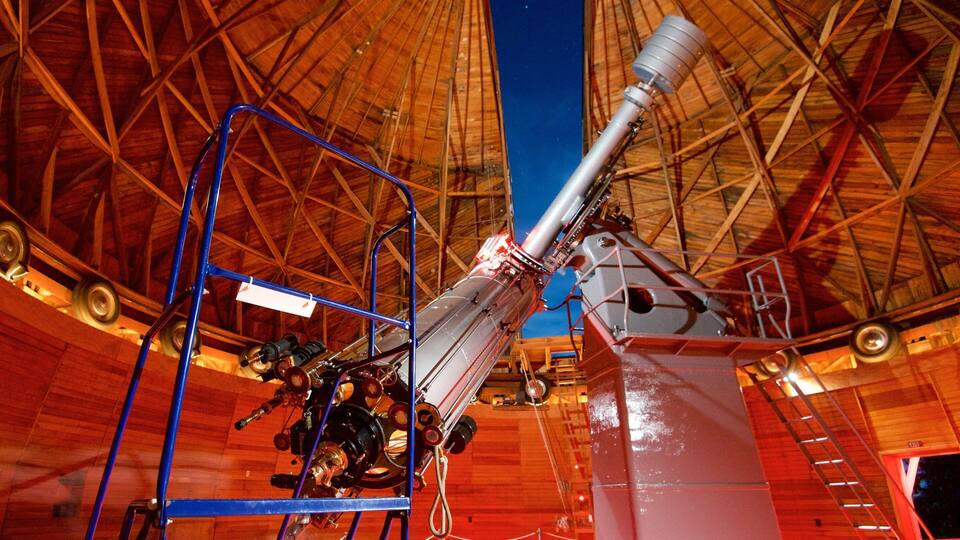 A large telescope with a wooden dome structure.