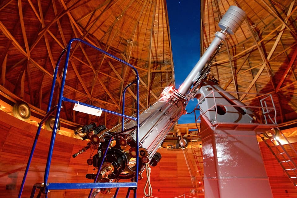 A large telescope with a wooden dome structure.
