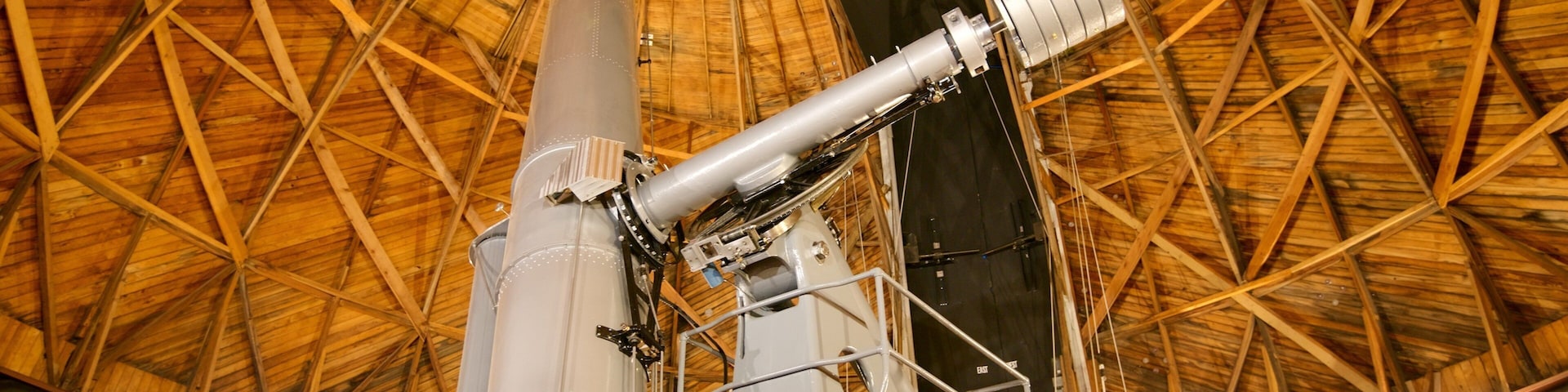 A large telescope with a wooden roof structure.