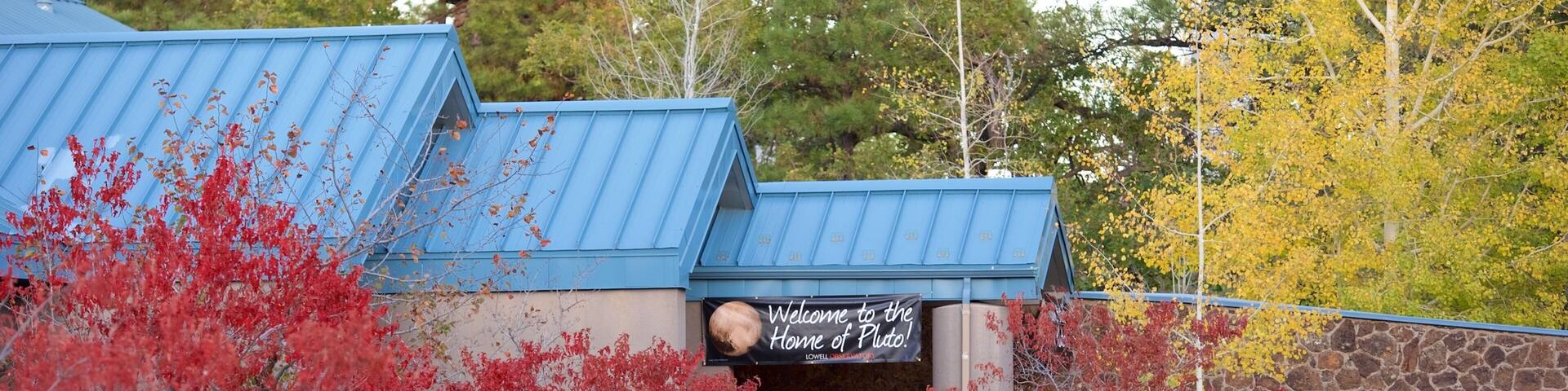 A building with a blue roof and a sign that reads "Welcome to the Home of Pluto."